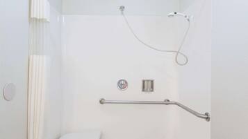 En dusch med ett stödhandtag, ett duschmunstycke som kan hållas i handen och en kontrollpanel.