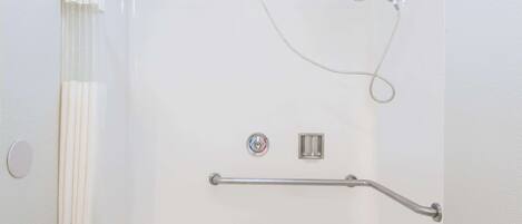 Una ducha con barra de apoyo, cabezal de ducha de mano y panel de control.