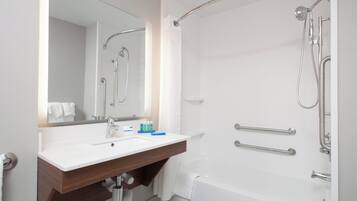 Un baño moderno con un lavamanos, espejo y ducha blancos.