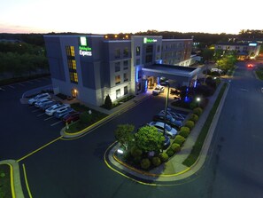 Un bâtiment de l’hôtel Holiday Inn Express avec un parking et une route devant.