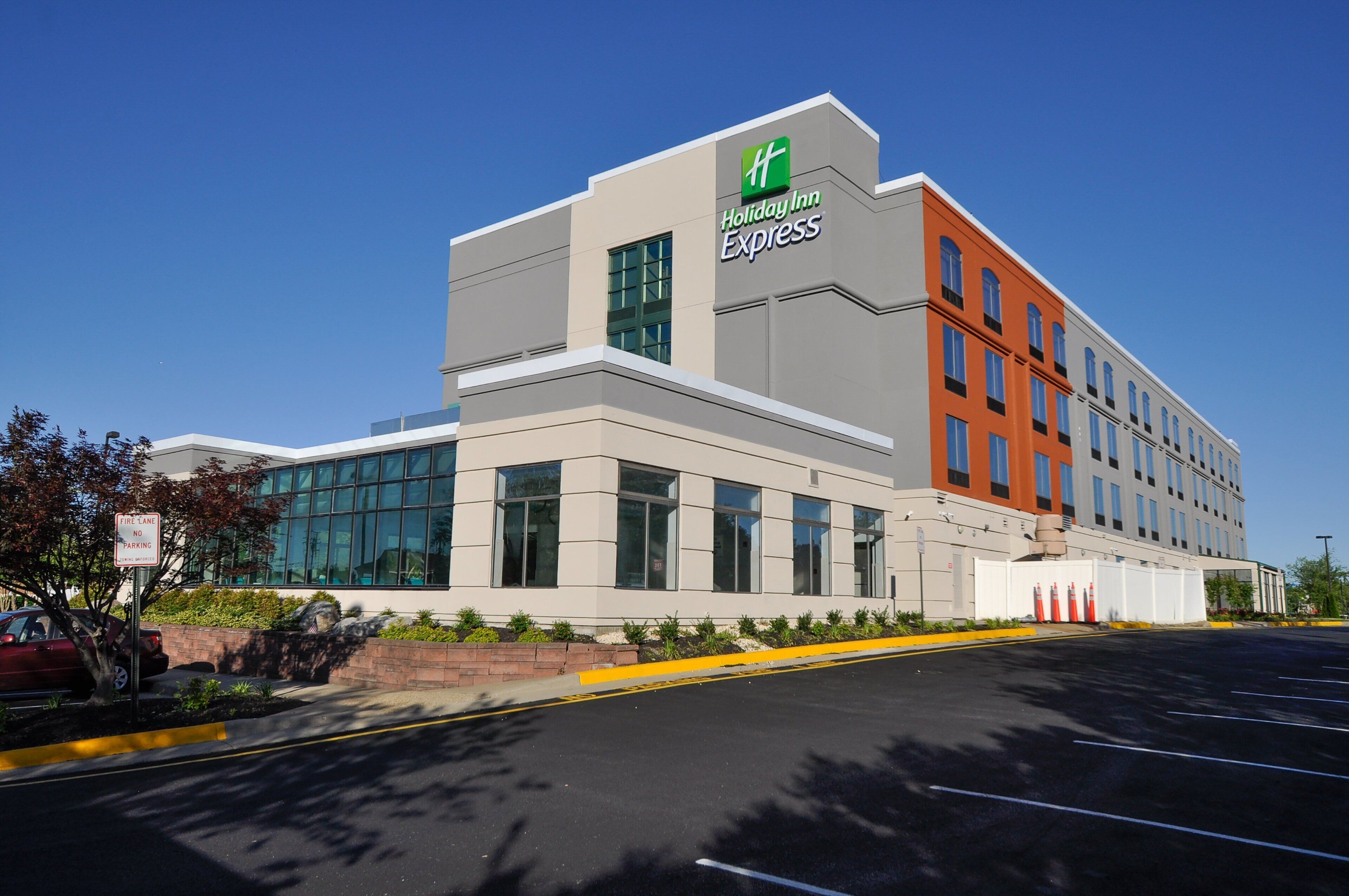 A Holiday Inn Express building with a modern architectural design, featuring large windows and a mix of grey and orange facades.