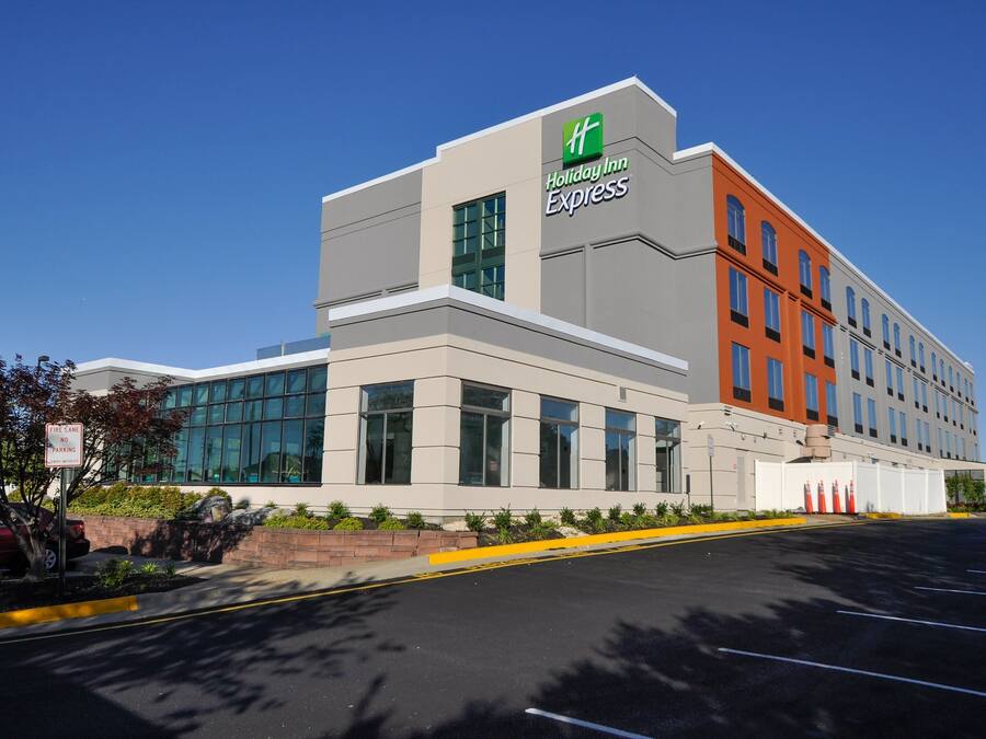 En Holiday Inn Express-byggnad med en modern arkitektonisk design, med stora fönster och en kombination av grå och orange fasader.