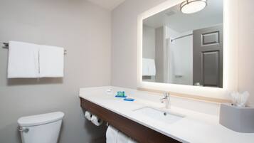 A modern bathroom with a white toilet, a sink with a mirror above it, and a towel rack above the toilet.
