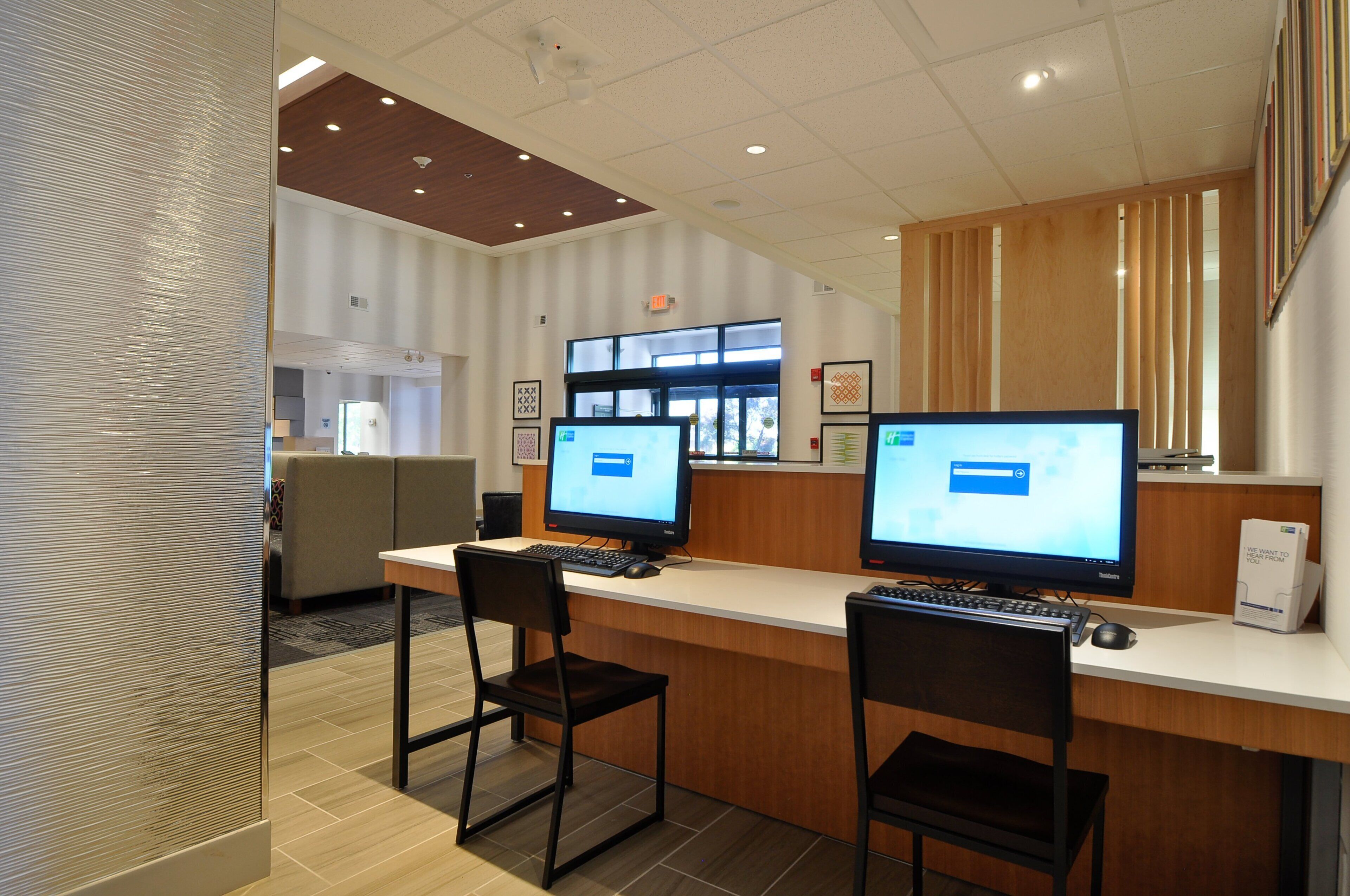A reception area with two computer monitors, a reception desk, and a seating area with chairs.