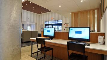 A reception area with two computer monitors, a reception desk, and a seating area with chairs.