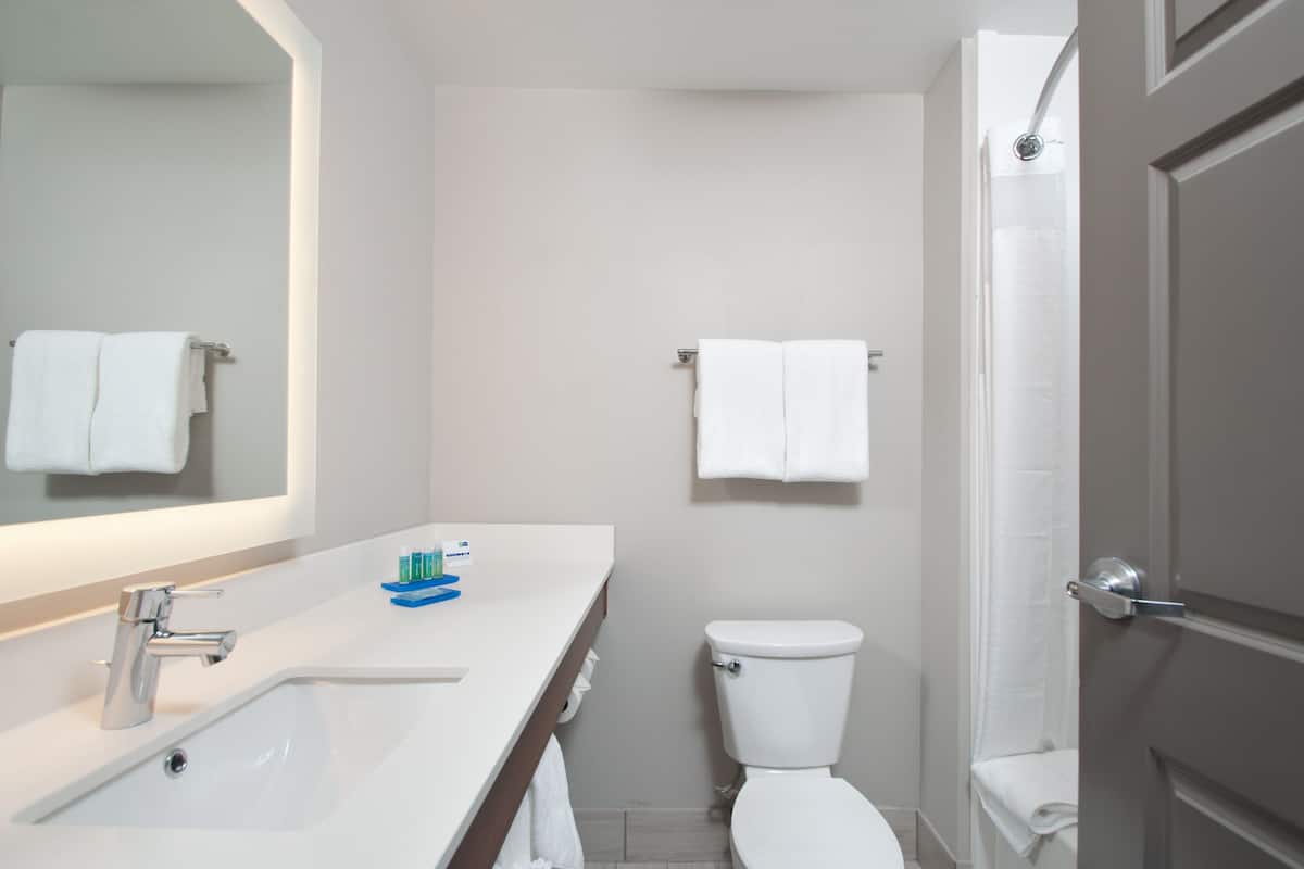 A modern bathroom with a white sink, mirror, and toilet.