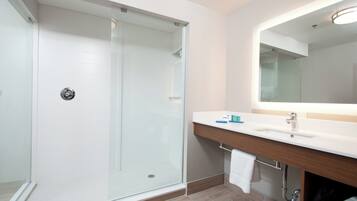 A modern bathroom with a glass-enclosed shower, a white sink, and a mirror above it.