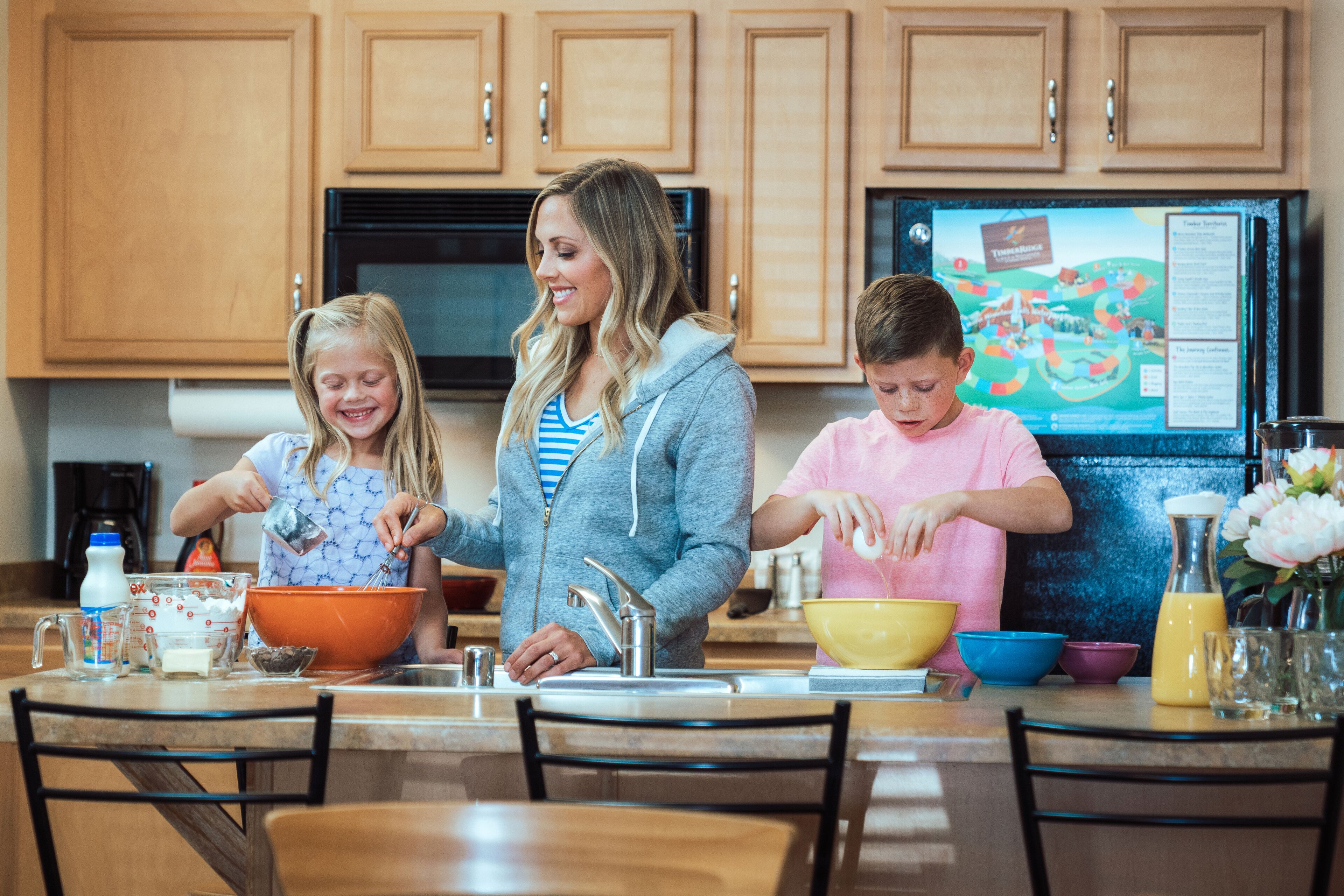 A kitchen with wooden cabinets, a refrigerator with a map, and a dining table with chairs.