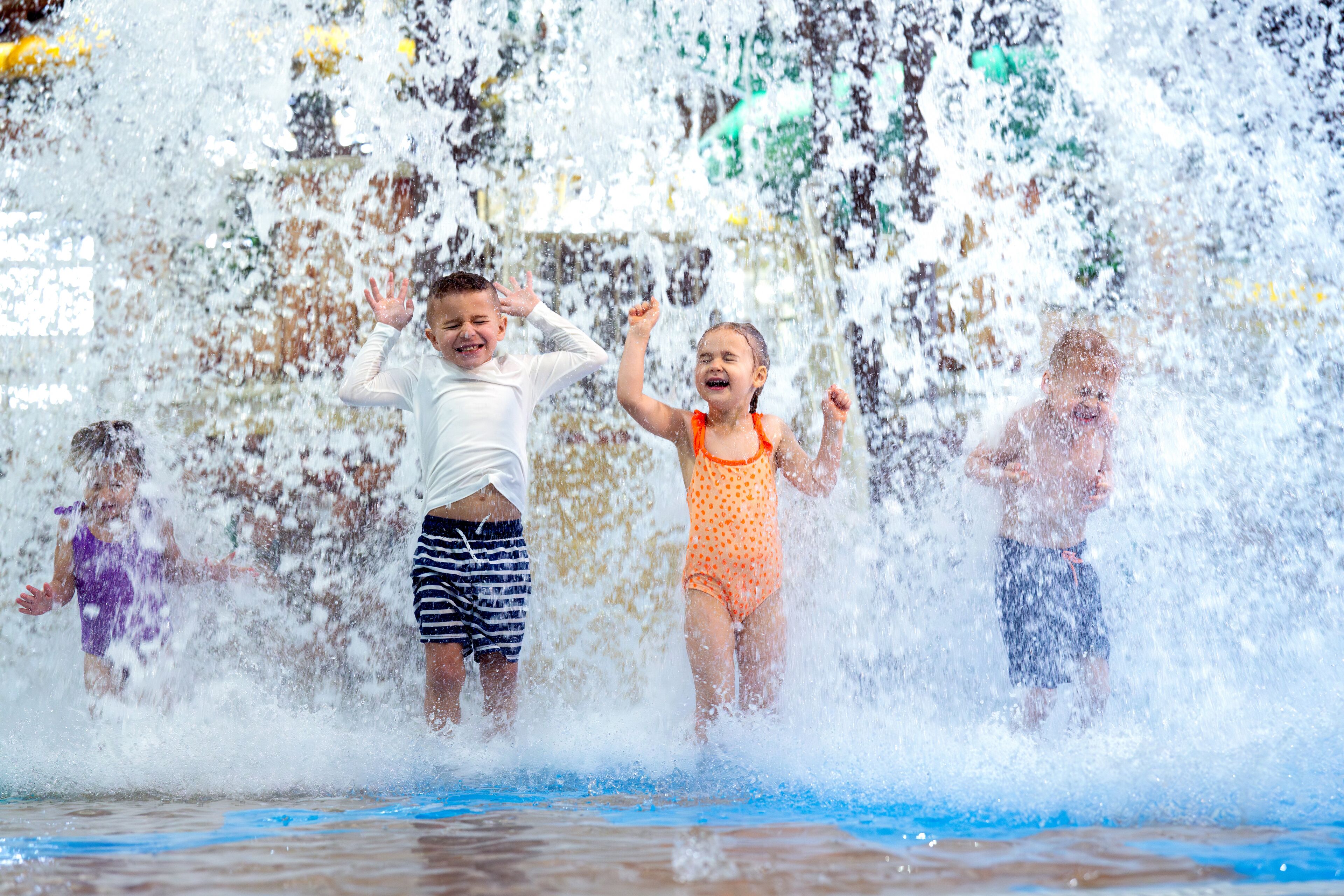Children playing in a water play area with a blue surface.