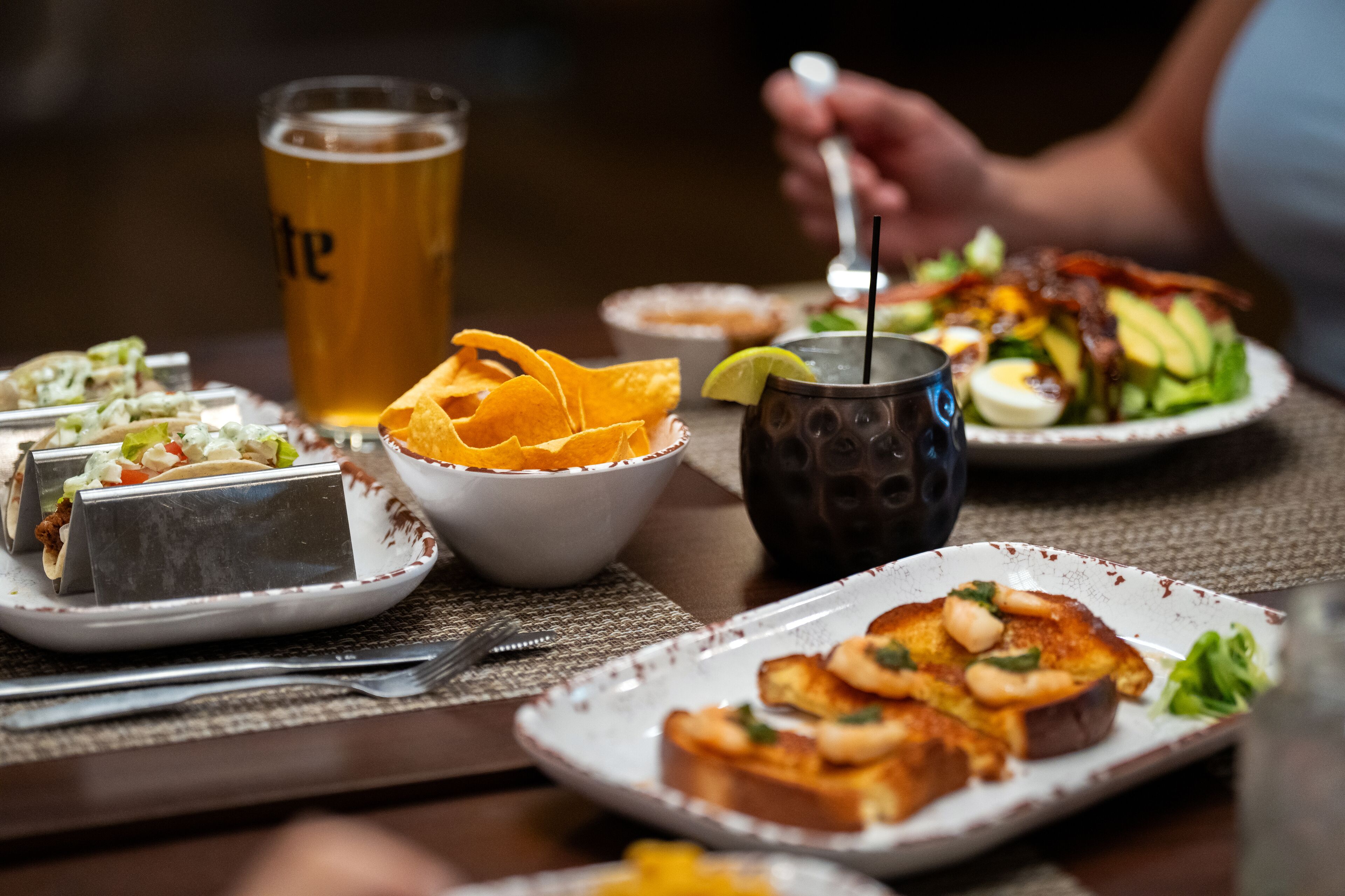 A dining table with various dishes, including tacos, a salad, and toast with avocado.