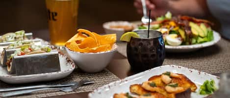 Una mesa de comedor con diferentes platillos, incluyendo tacos, ensalada y tostadas con aguacate.