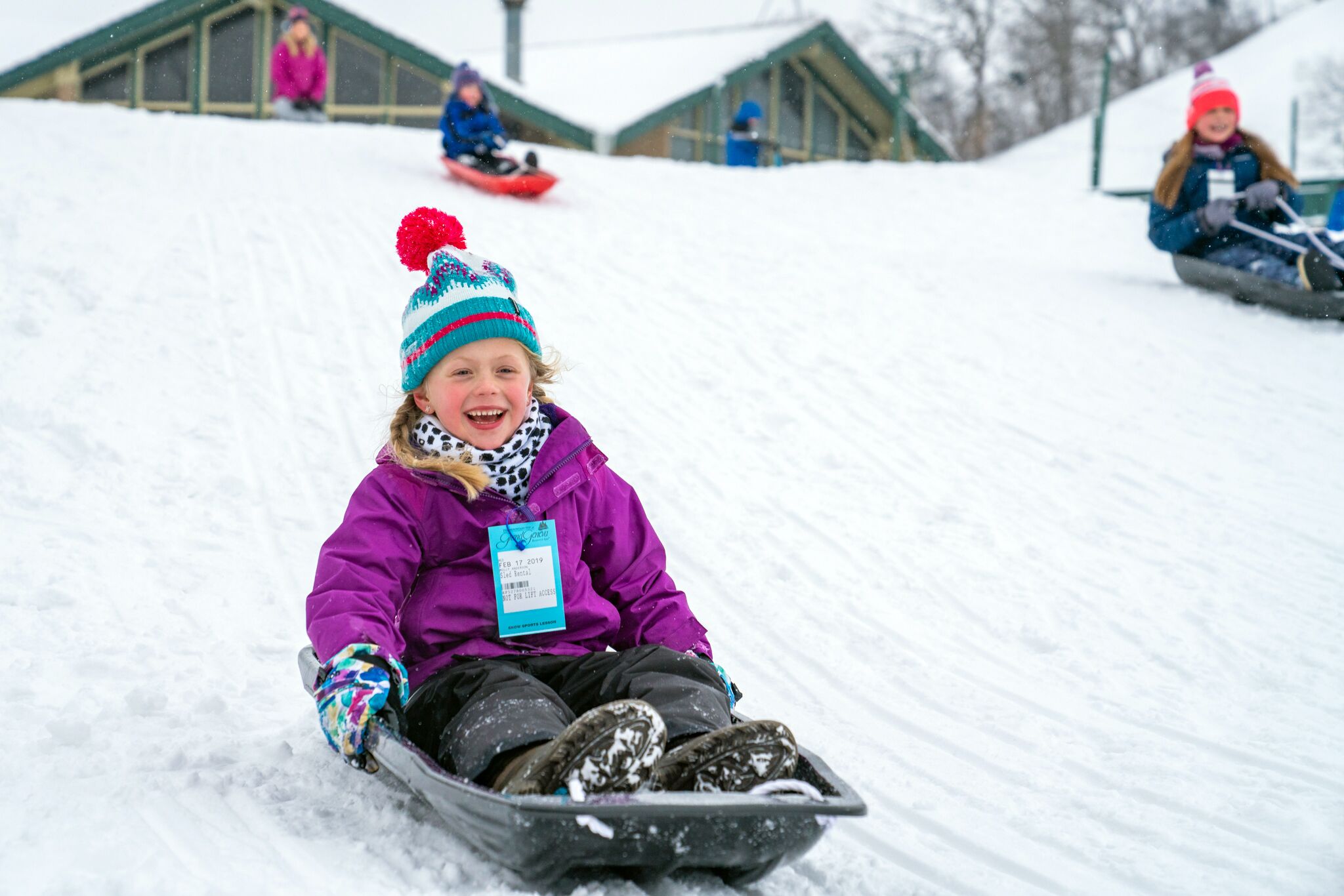 A child sledding down a snowy slope.