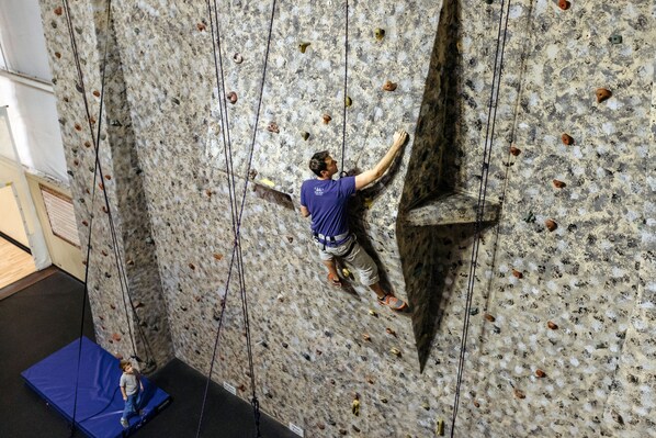A person climbing a rock wall with handholds and footholds.