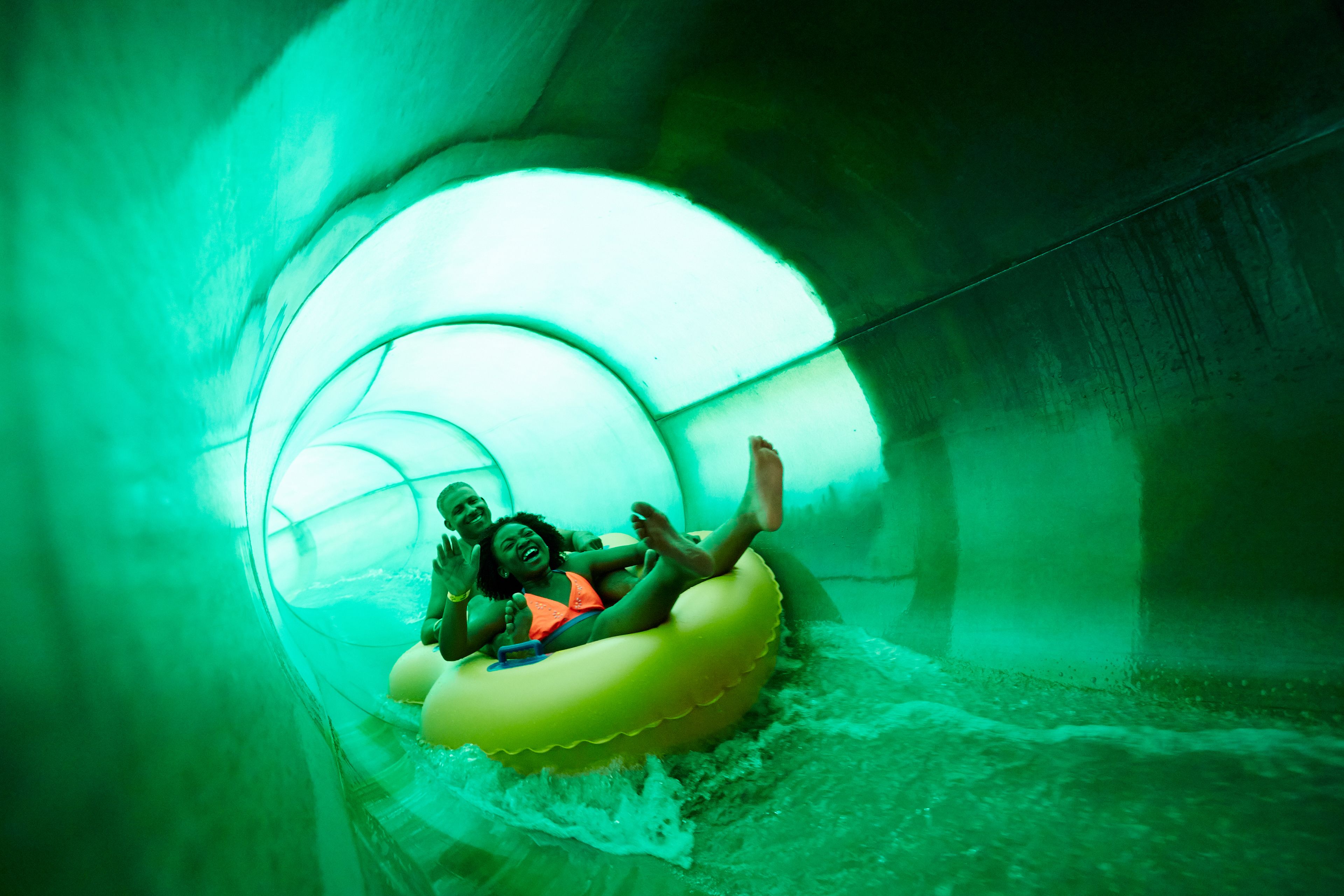 A water slide with a transparent tube and inflatable raft.