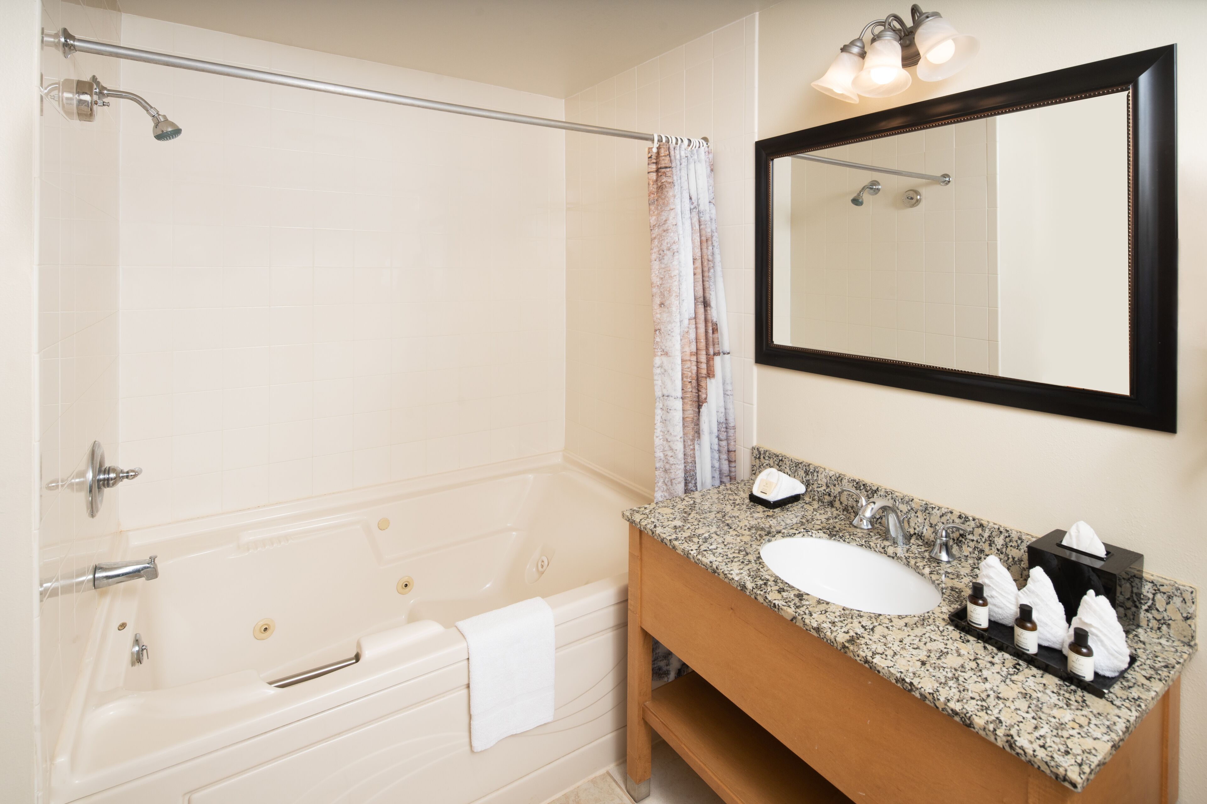 A bathroom with a bathtub, a sink, a mirror, and a towel rack.