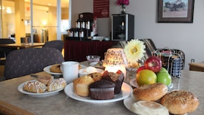 A breakfast table with pastries, fruits, and a lamp.