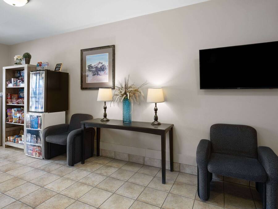 Una sala de estar con dos sillones, una mesa de centro, un televisor, una estantería y un refrigerador.