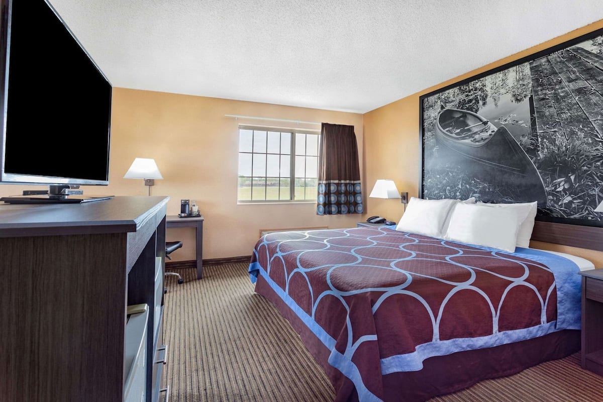 Une chambre d’hôtel avec un lit, un bureau, une télévision et une grande fenêtre.