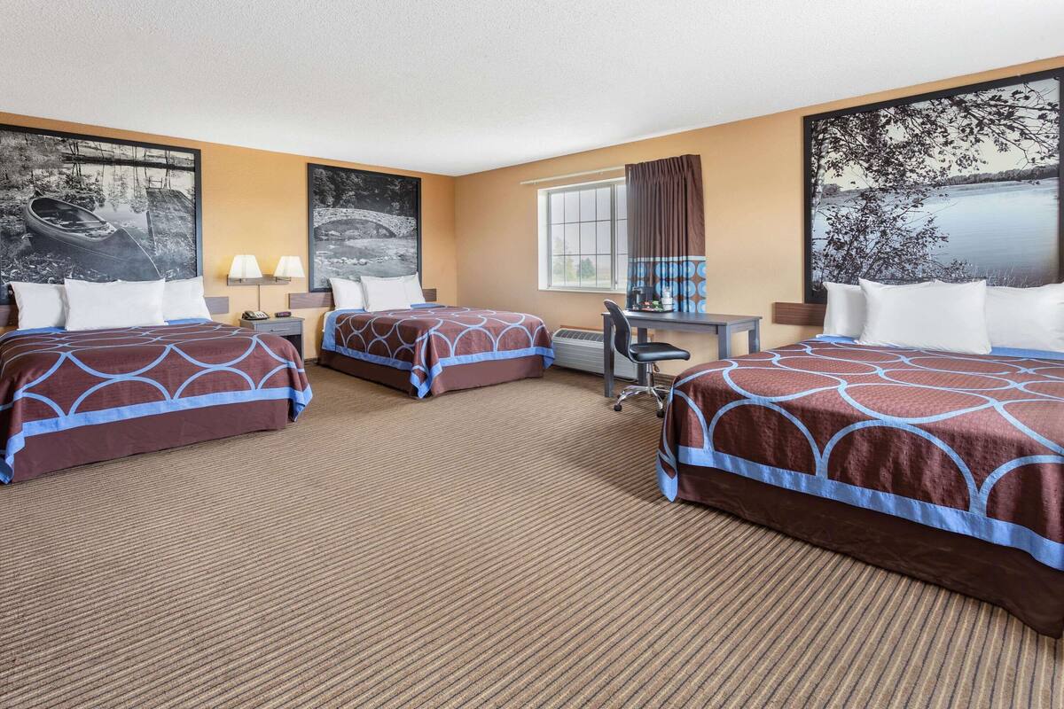 Une chambre d’hôtel avec deux lits, un bureau et une chaise.