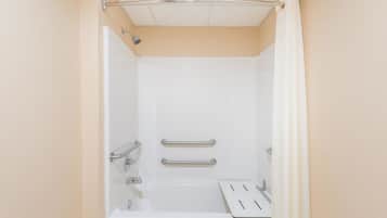 Una bañera blanca estándar con barras de apoyo, cabezal de ducha y panel de control.