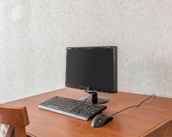 Un escritorio de madera con un monitor negro, teclado y ratón.