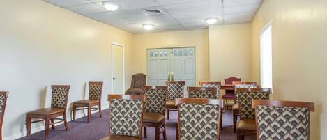 A conference room with wooden chairs and tables, a ceiling with recessed lighting, and a door with frosted glass panels.