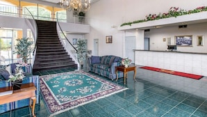 Un hall d’entrée spacieux, agrémenté d’un magnifique escalier, d’un comptoir de réception et d’un grand lustre.