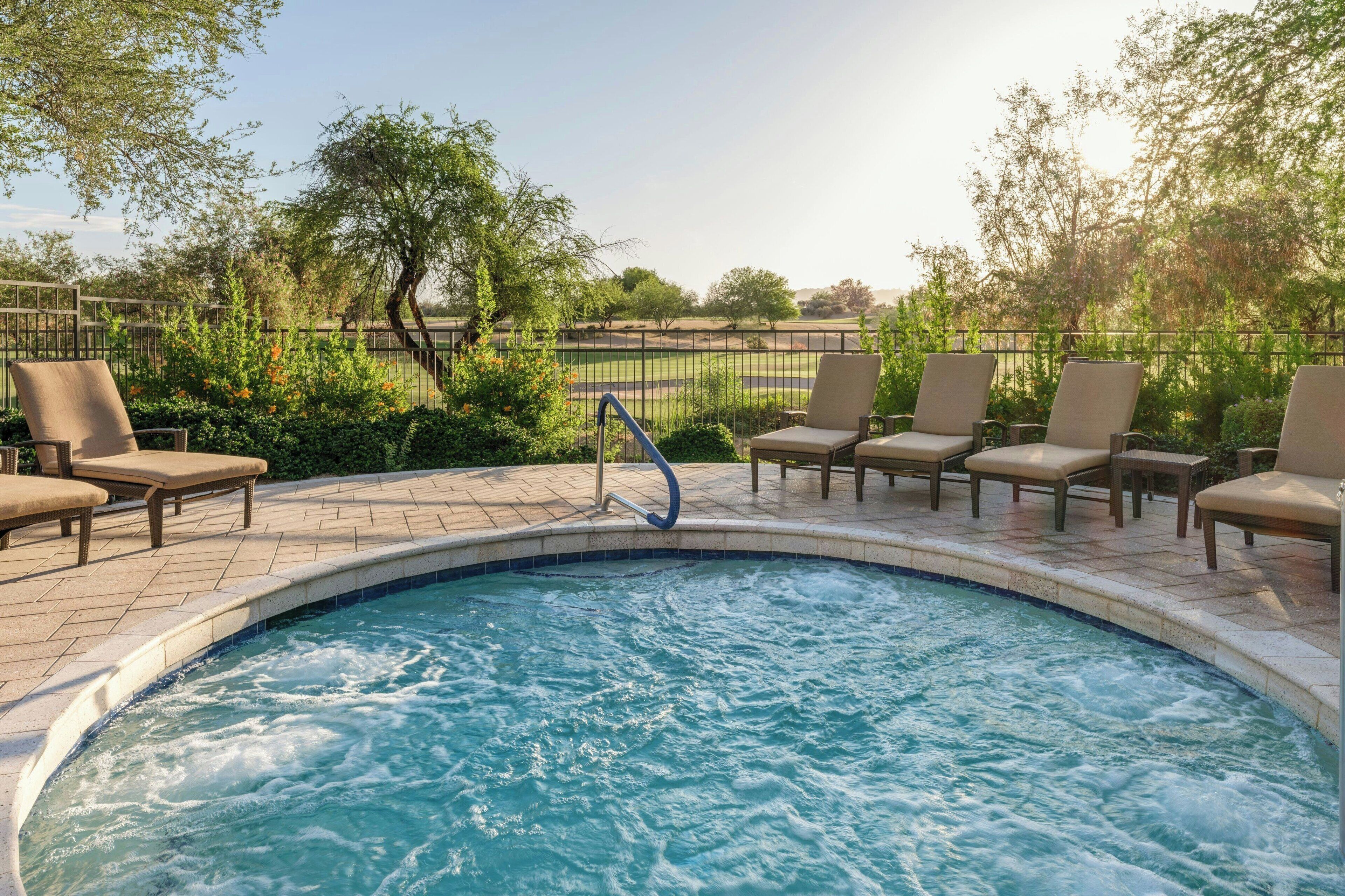 A swimming pool with lounge chairs and a metal fence.