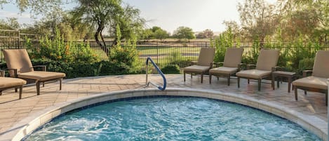 A swimming pool with lounge chairs and a metal fence.