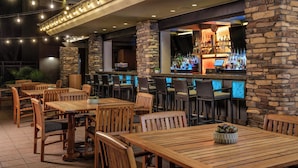 An outdoor bar area with stone pillars, wooden tables and chairs, and string lights. - The Westin Kierland Villas, Scottsdale (Scottsdale)