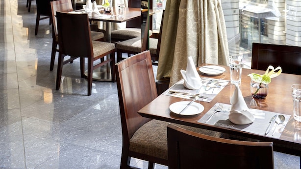 A long dining area with tables set for service, large windows with curtains, and hanging light fixtures. - The Kowloon Hotel (Kowloon)