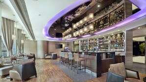 A modern bar area with a curved ceiling, bar stools, and a variety of liquor bottles. - The Kowloon Hotel (Kowloon)