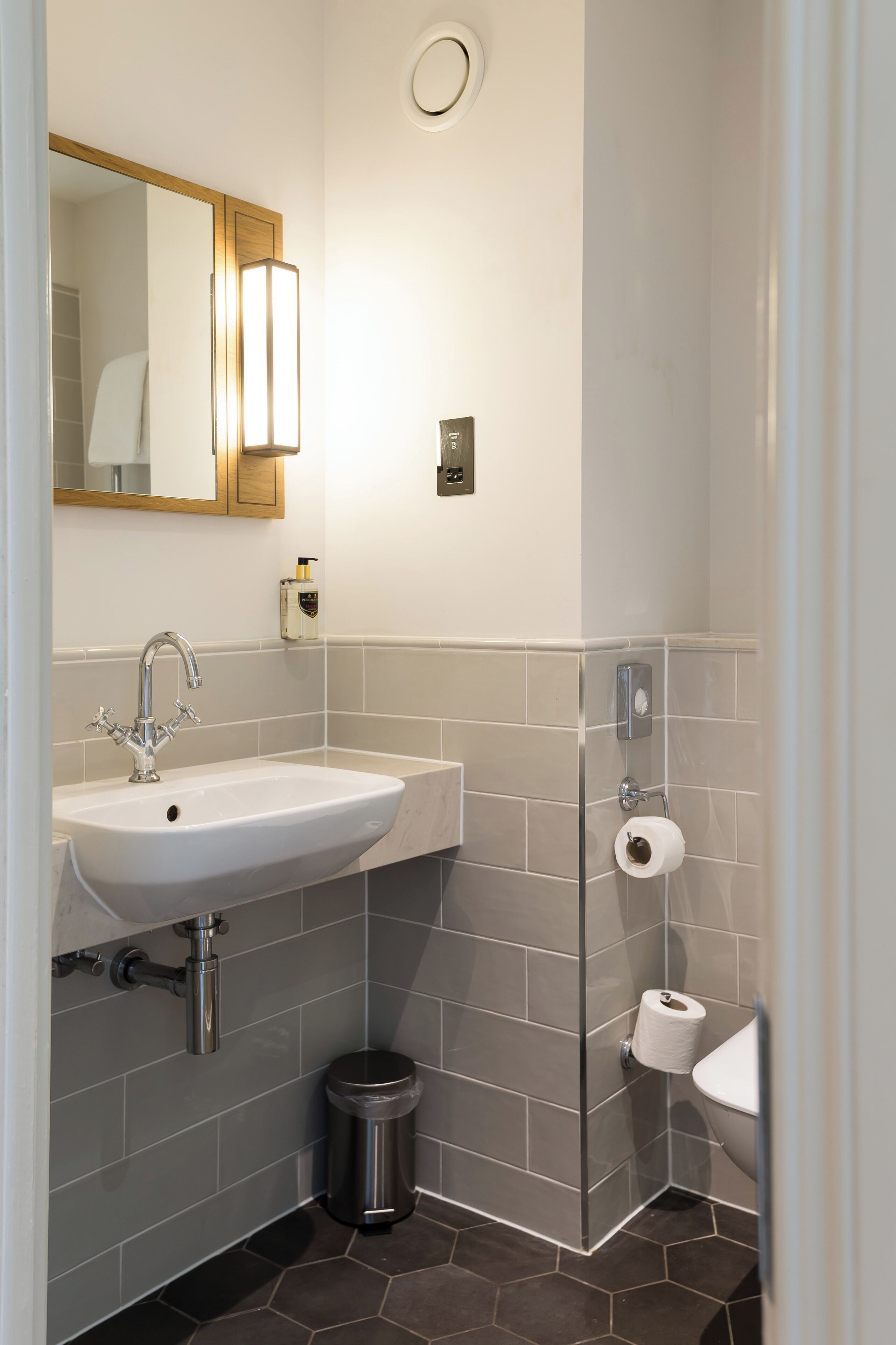 A modern bathroom with a white sink, a mirror, and a shower area.