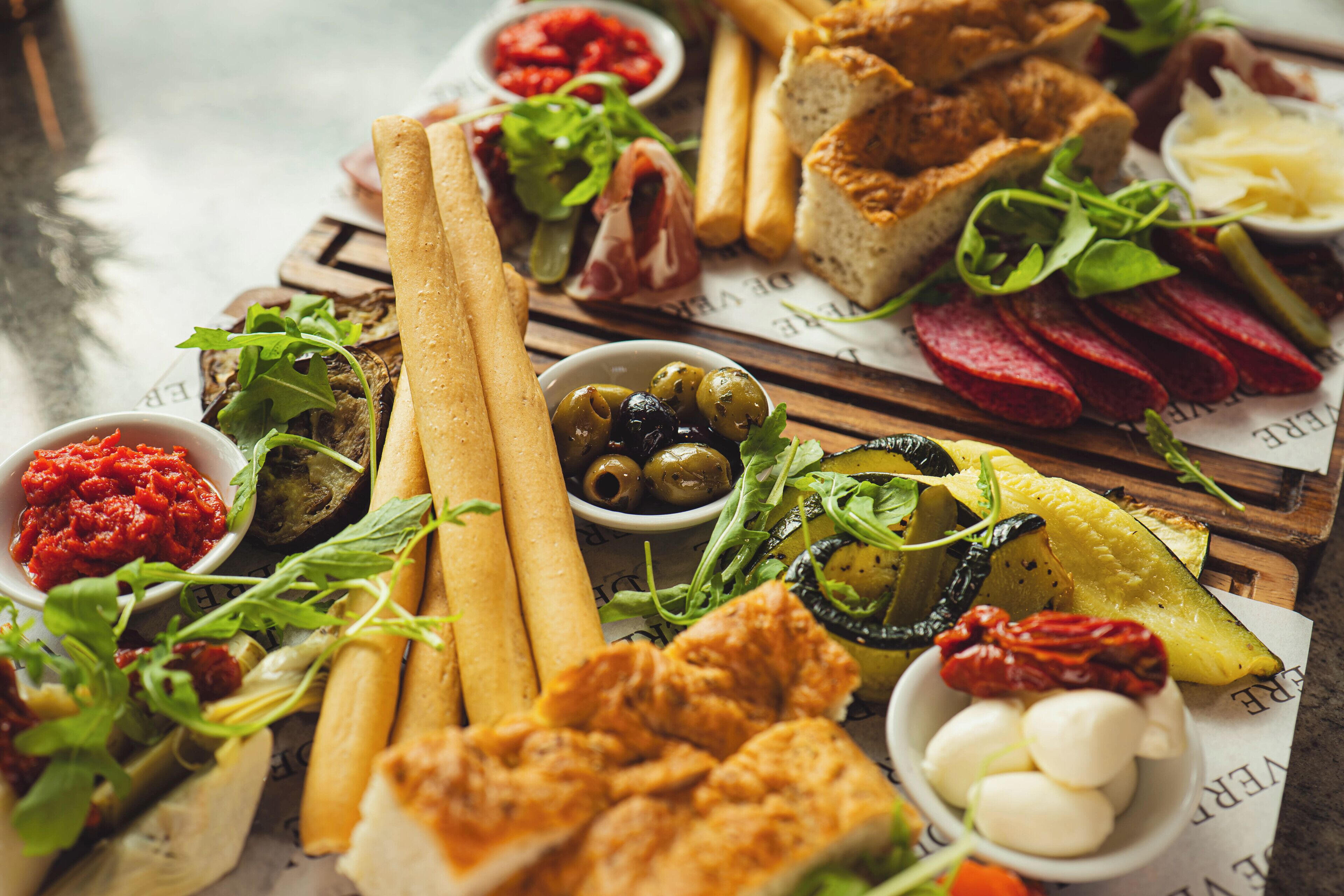 A variety of food items including bread, olives, and meats arranged on a wooden board.