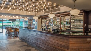 A bar area with wooden paneling, hanging light fixtures, and a variety of bottles and glasses on shelves. - De Vere Wokefield Estate (Reading)