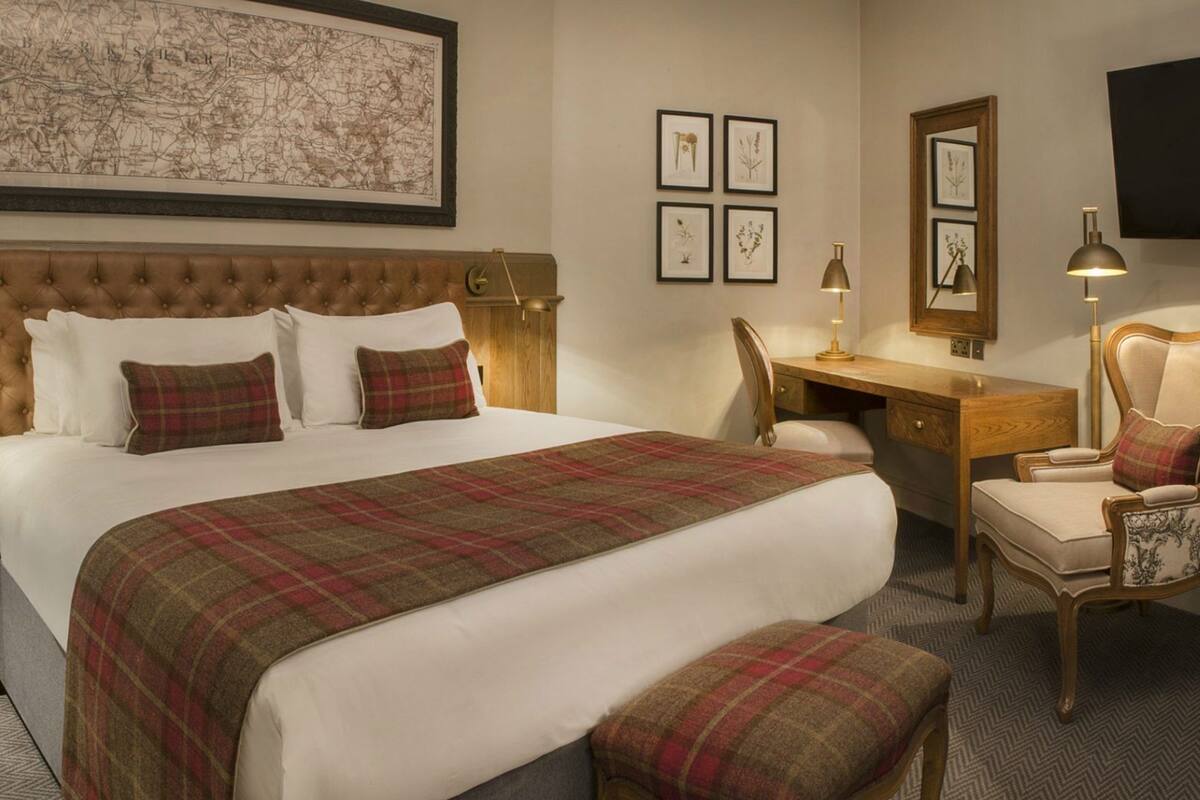 A hotel room with a large bed, a desk, a chair, and a map on the wall.