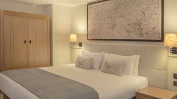 Een netjes opgemaakt bed met hoofdbord, twee bedlampen, een grote inlijsting kaart aan de muur en een houten garderobe.