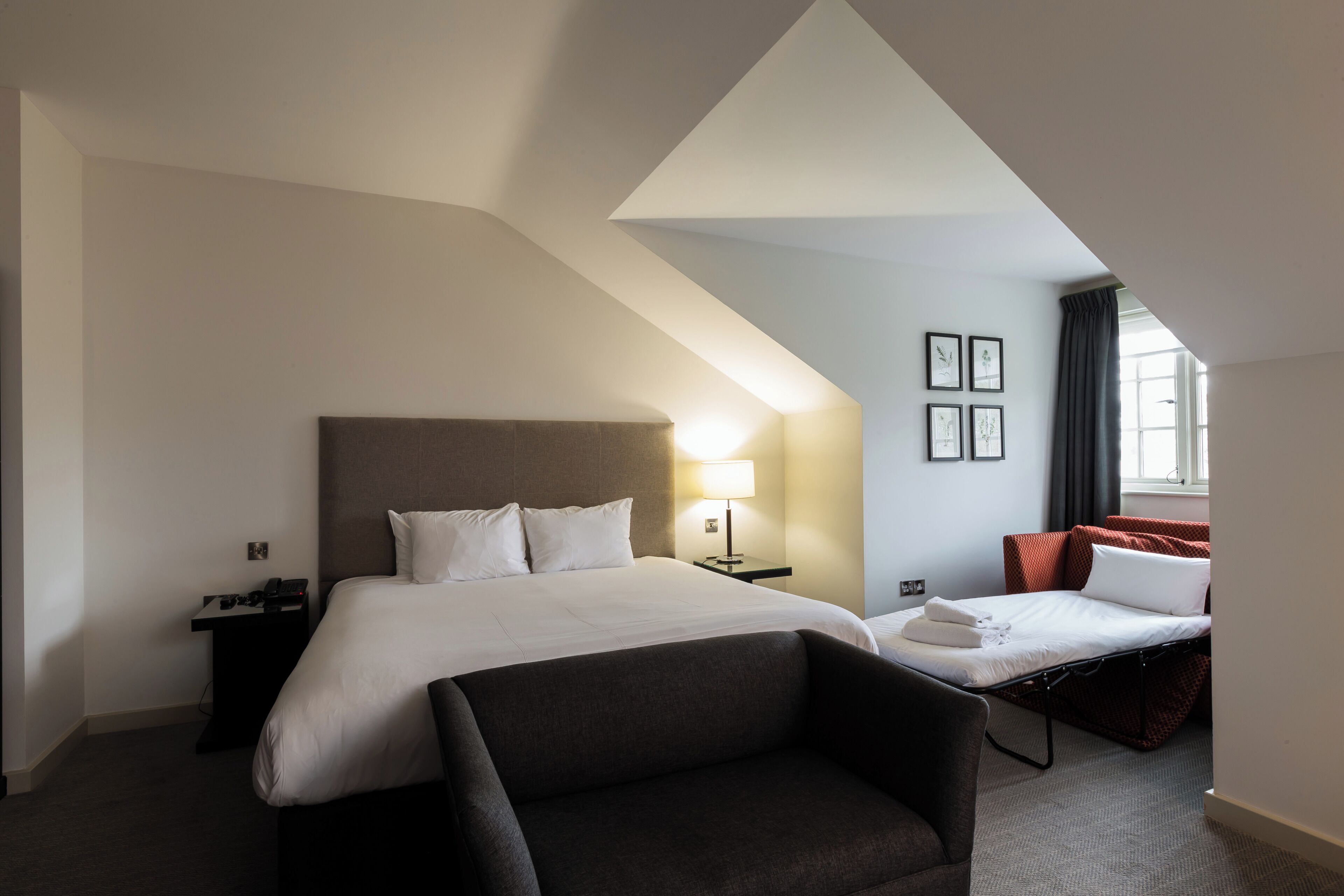Una habitación de hotel con cama, escritorio, silla y un pequeño sofá.