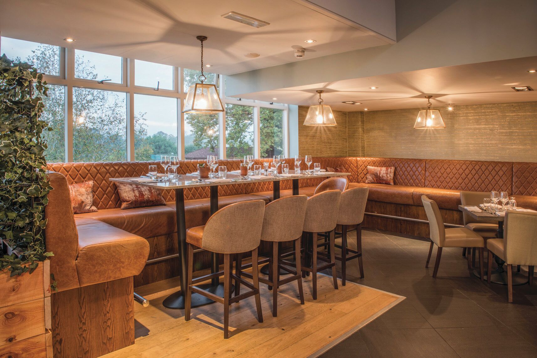 Un restaurante con una larga mesa de madera, asientos acolchados e iluminación colgante.