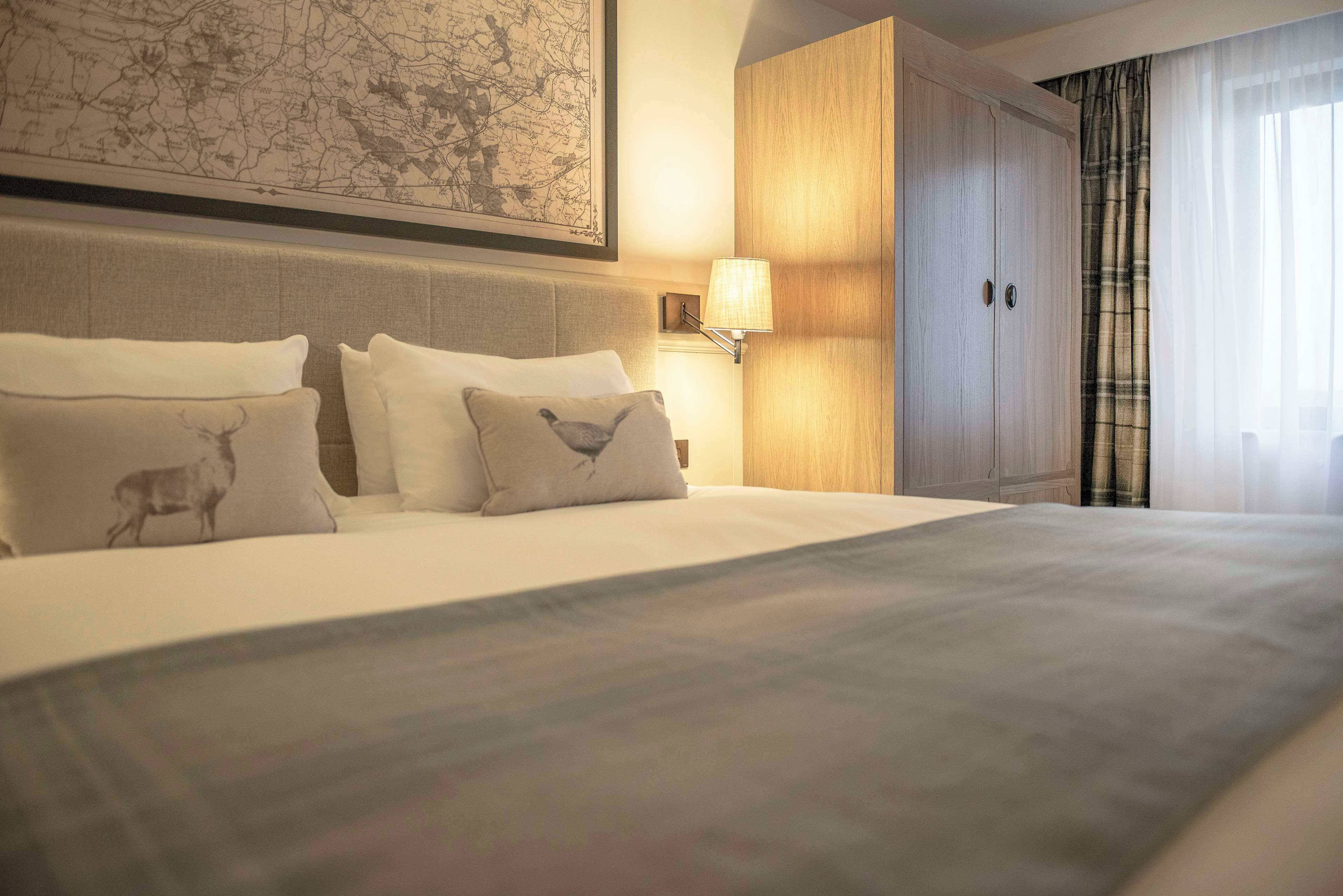 A neatly made bed with two pillows, a wall-mounted map, a bedside lamp, and a wardrobe.