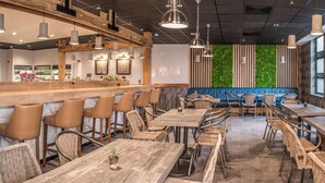 A modern restaurant interior with wooden tables and chairs, a bar area, and a green vertical garden wall. - De Vere Wokefield Estate (Reading)
