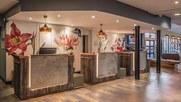 A reception area with wooden reception desks, a large floral mural, and a television screen.