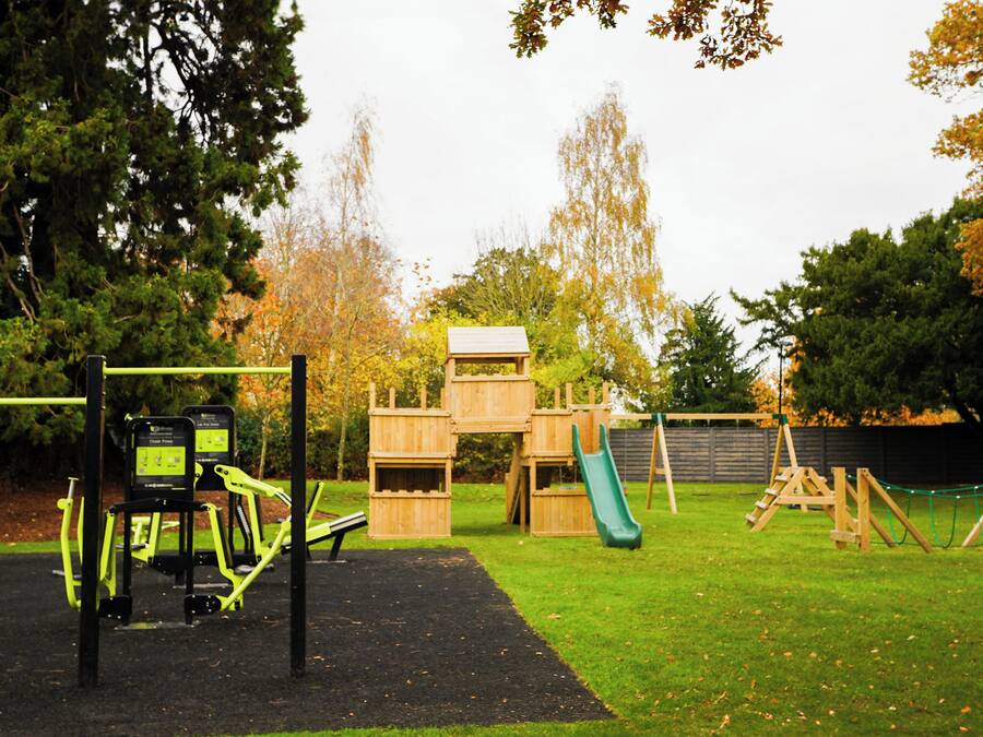 A playground with a slide, climbing structures, and exercise equipment.