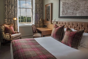 A hotel room with a large bed, a desk, a chair, and a map on the wall.