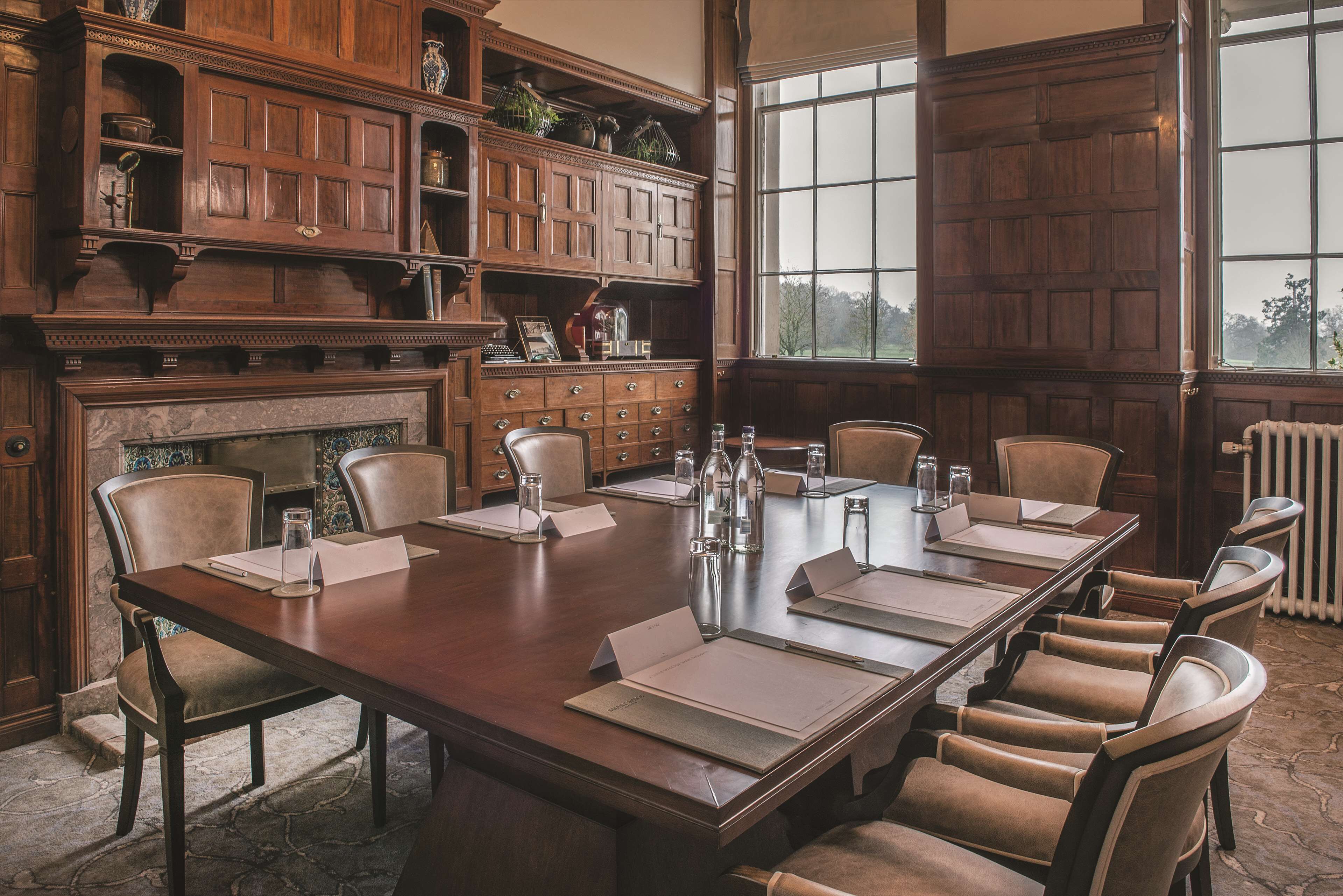 A conference room with a long wooden table, multiple chairs, and a fireplace.