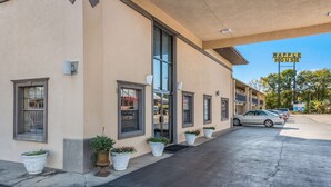 A building with a sign reading "WAFFLE HOUSE" on the right, a parking lot with several cars, and potted plants along the sidewalk. - Americas Best Value Inn & Suites Arkadelphia (Arkadelphia)