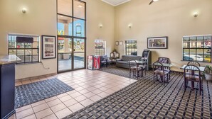 A hotel lobby with a reception desk, seating area, and large windows offering views of the outside. - Americas Best Value Inn & Suites Arkadelphia (Arkadelphia)
