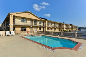 A motel with a swimming pool, multiple balconies, and a parking lot.