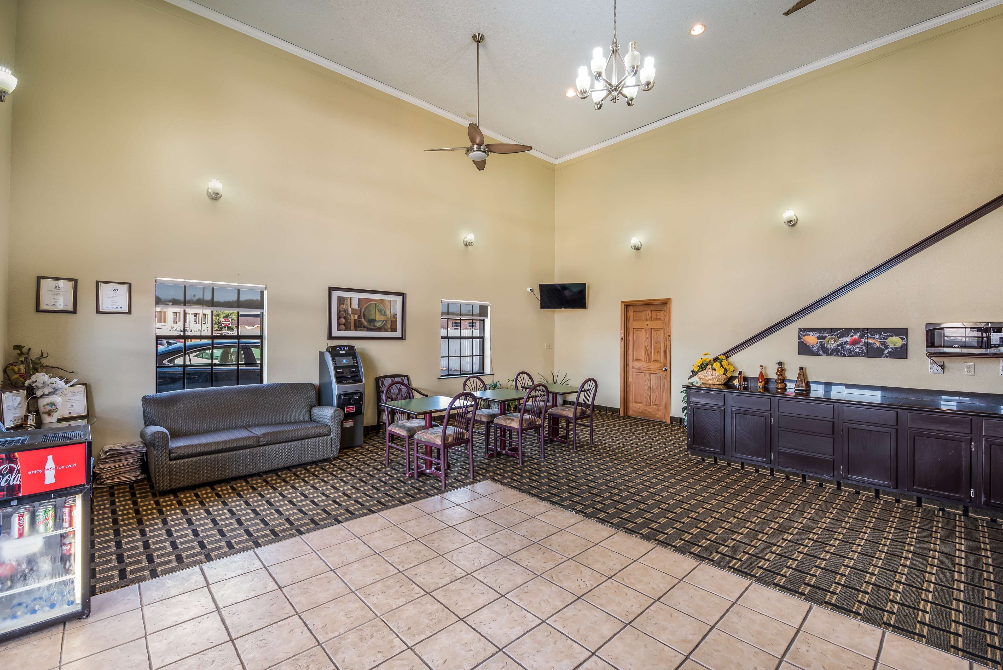 A spacious living area with a sofa, dining table, and chairs, a kitchen area with cabinets, a ceiling fan, and a chandelier.