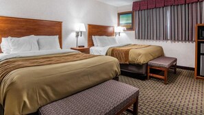 A hotel room with two beds, a ceiling fan, a window with curtains, and a small table. - Rodeway Inn Elko Downtown Area (Elko)